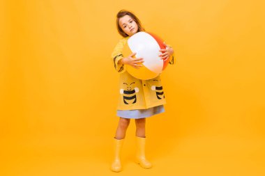 Topla turuncu arka planda poz veren sevimli küçük bir kız. 