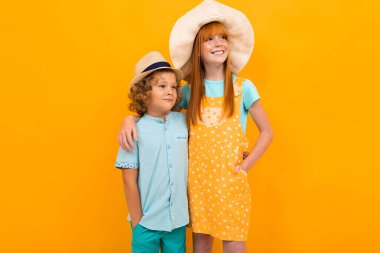 Tatlı çocuk ve kız turuncu arka planda poz veriyorlar. 