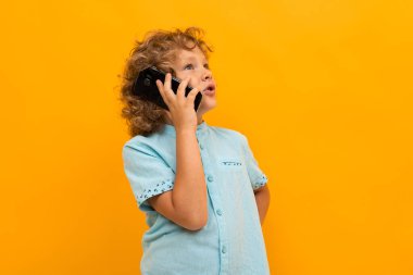 Küçük çocuk turuncu arka planda poz veriyor 