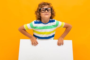 Küçük çocuk turuncu arka planda poz veriyor 