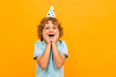 Küçük çocuk turuncu arka planda poz veriyor 