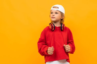 Stüdyoda turuncu arka planda poz veren şık bir çocuk. 