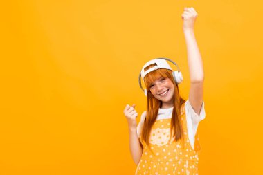 Neşeli kızıl kız turuncu arka planda müzik dinliyor. 