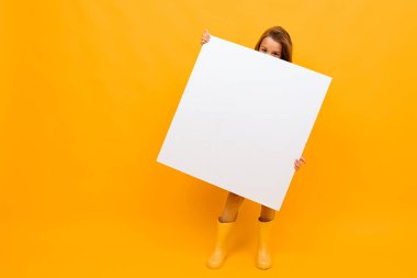 Turuncu arka planda beyaz tahtası olan küçük kız. 