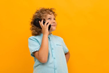 Küçük çocuk turuncu arka planda poz veriyor 