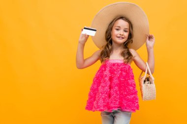 Küçük kız kredi kartıyla turuncu arka planda poz veren bayan gibidir. 