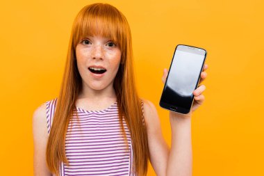 ginger girl with smartphone against orange background 