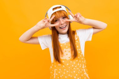 Neşeli kızıl kız turuncu arka planda müzik dinliyor. 