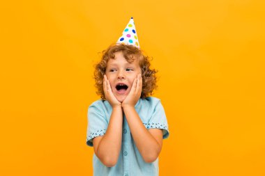 Küçük çocuk turuncu arka planda poz veriyor 