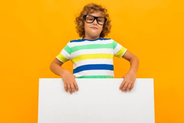 Küçük çocuk turuncu arka planda poz veriyor 