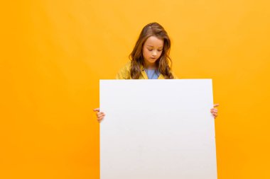 Turuncu arka planda beyaz tahtası olan küçük kız. 