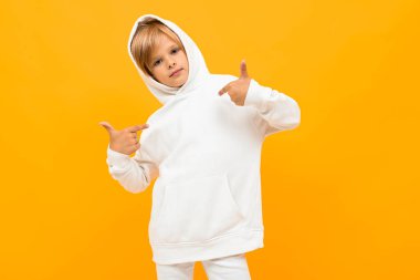 Beyaz kapüşonlu duygusal çocuk turuncu arka planda poz veriyor