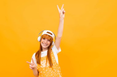 Neşeli kızıl kız turuncu arka planda müzik dinliyor. 