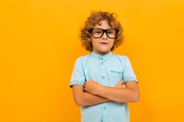 Küçük çocuk turuncu arka planda poz veriyor 