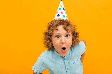 Küçük çocuk turuncu arka planda poz veriyor 