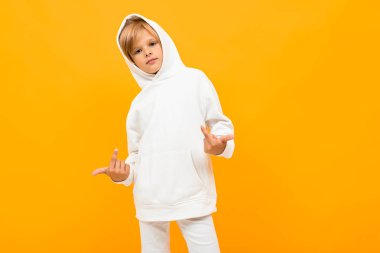 Beyaz kapüşonlu duygusal çocuk turuncu arka planda poz veriyor