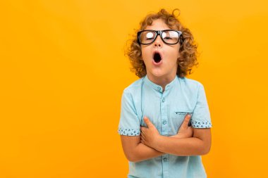 Küçük çocuk turuncu arka planda poz veriyor 