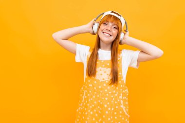 Neşeli kızıl kız turuncu arka planda müzik dinliyor. 