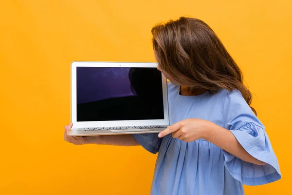 cute little girl with laptop against orange background