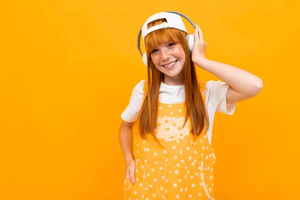 Веселая Рыжая Девушка Слушает Музыку Оранжевом Фоне — стоковое фото
