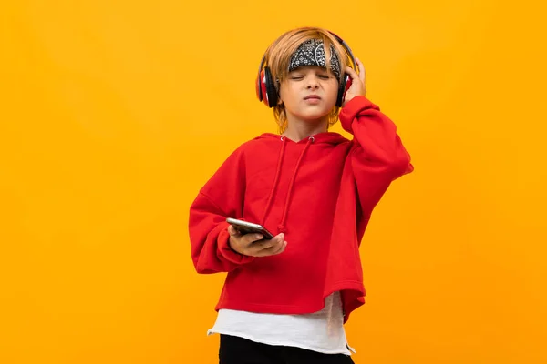fashionable boy with phone and headphones against orange