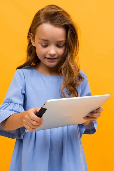 Schattig Klein Meisje Met Tablet Poseren Tegen Oranje Achtergrond — Stockfoto