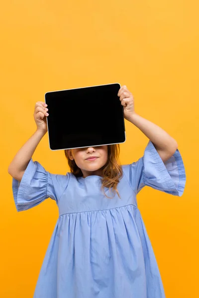 Cute Little Girl Tabletkami Pozowanie Pomarańczowym Tle — Zdjęcie stockowe