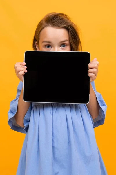 Cute Little Girl Tabletkami Pozowanie Pomarańczowym Tle — Zdjęcie stockowe