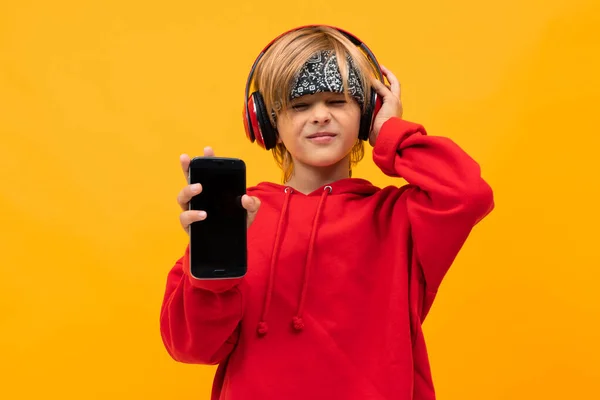 fashionable boy with phone and headphones against orange