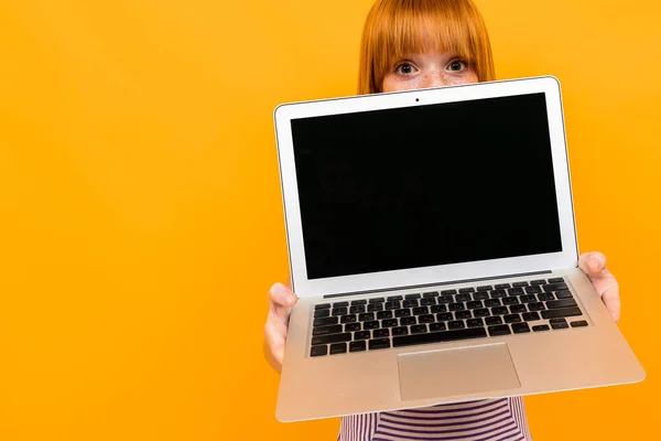 ginger cute girl with laptop against orange background