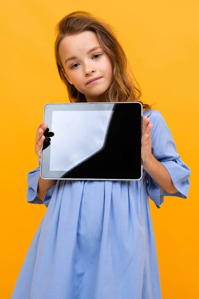 Cute Little Girl Tabletkami Pozowanie Pomarańczowym Tle — Zdjęcie stockowe