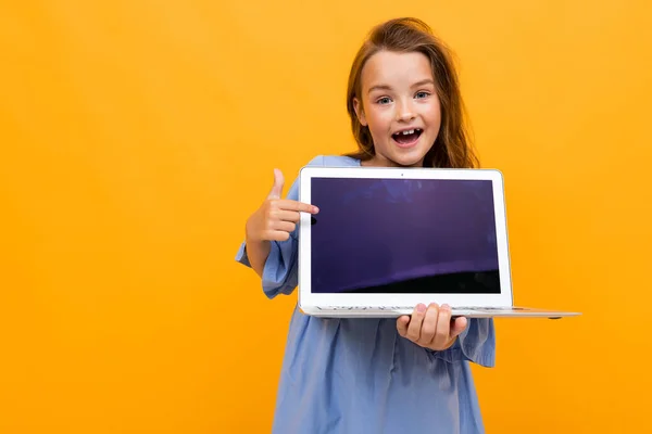 cute little girl with laptop against orange background