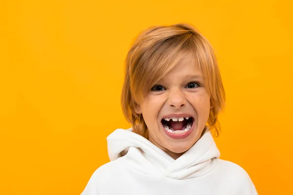 Emotivní Chlapec Bílé Mikině Pózuje Proti Oranžovému Pozadí — Stock fotografie