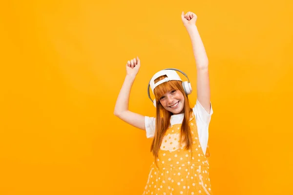 Fröhliches Ingwermädchen Das Musik Hört Und Vor Orangefarbenem Hintergrund Posiert — Stockfoto