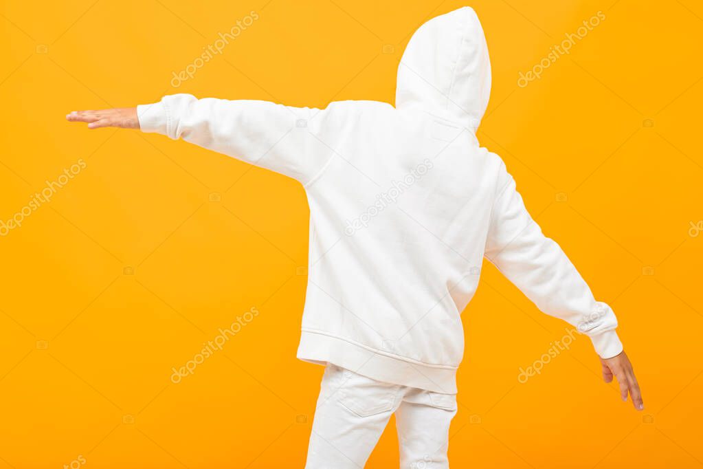 emotional boy in white hoodie posing against orange background