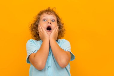 Küçük çocuk turuncu arka planda poz veriyor 