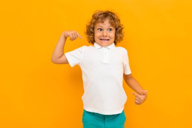 Küçük çocuk turuncu arka planda poz veriyor 