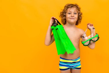 Küçük çocuk turuncu arka planda sahilde poz veriyor. 