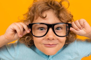 Küçük çocuk turuncu arka planda poz veriyor 