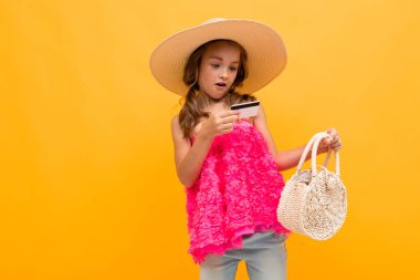 Küçük kız kredi kartıyla turuncu arka planda poz veren bayan gibidir. 