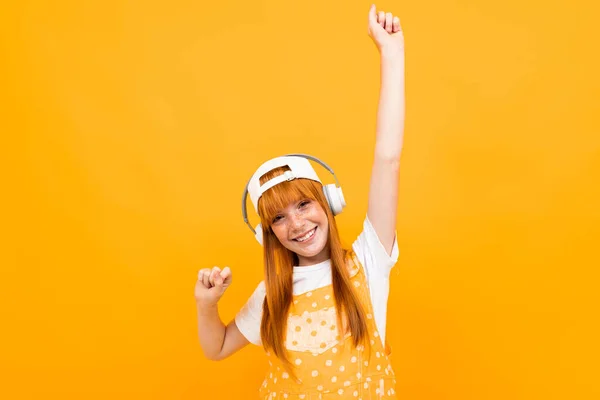 Fröhliches Ingwermädchen Das Musik Hört Und Vor Orangefarbenem Hintergrund Posiert — Stockfoto