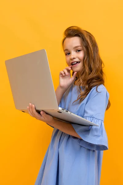 Portakal Rengi Arka Planda Dizüstü Bilgisayarı Olan Tatlı Bir Kız — Stok fotoğraf