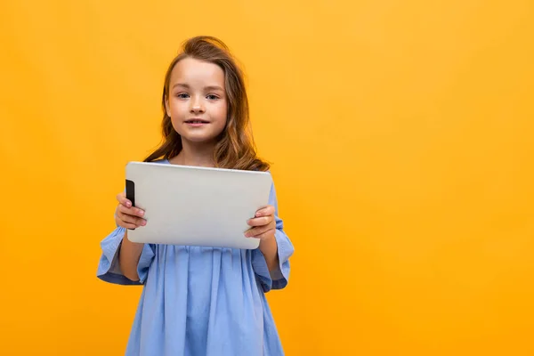 Cute Little Girl Tabletkami Pozowanie Pomarańczowym Tle — Zdjęcie stockowe