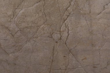 Bu sahnede, belirgin çatlaklar ve toprak renkleri olan desenli bir yüzeye sahip doğal taşın yakın çekimi sergileniyor. Tasarım ham ve organik bir görünüm yaratıyor..