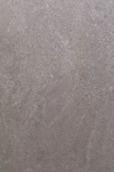 Resim, çeşitli dokuları ve ince renk değişimleriyle gri bir taş yüzeyin yakın çekimini gösteriyor. Doğal desenler ilginç bir görsel cazibe ve derinlik yaratır..
