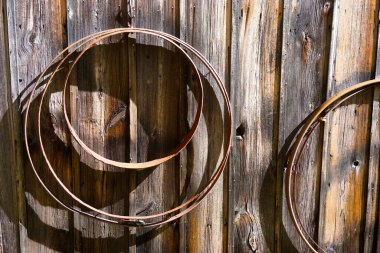 Paslı metal fıçı jantlar eski bir ahırın dışındaki çiviye asılı..