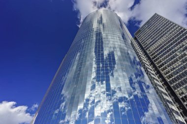 New York, New York: Mavi gökyüzündeki bulutlar, Manhattan 'ın Battery Park bölgesindeki 17 State Street' teki modern bir gökdelenin çelik ve cam cephesine yansımaktadır (1988)..