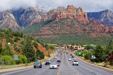 Sedona, Arizona: Arka planda kırmızı kayaların üzerinde bulutların gezindiği Sedona manzarası.
