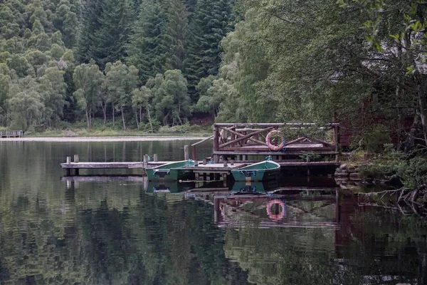 苏格兰高地一个宁静的湖面上的小木屋甲板上绑着的罗浮船 — 图库照片