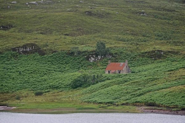 苏格兰高地西海岸一个湖边的山坡上的一座废弃的红屋 — 图库照片